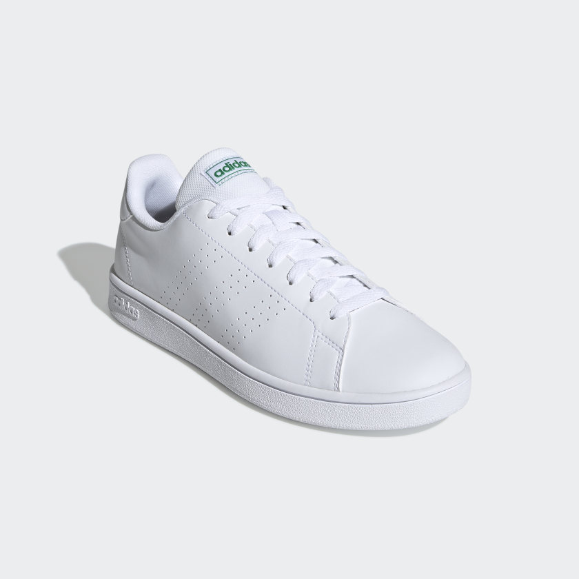 ténis Adidas branco com logótipo verde sobre fundo branco