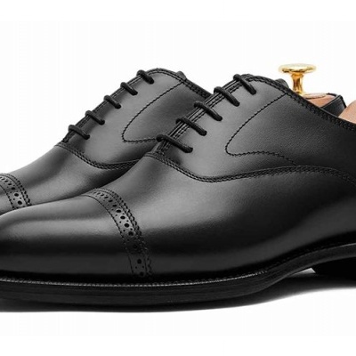 Sapatos sociais pretos de couro com detalhes perfurados e atacadores.