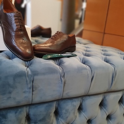 Sapatos sociais de couro castanho sobre sofá azul claro em loja