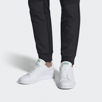 Ténis brancos Adidas com detalhes verdes usados com calças pretas