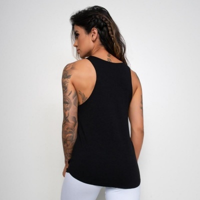 Mulher de costas com tshirt preta sem mangas e calças brancas