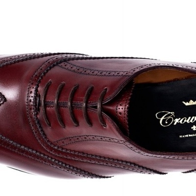 Sapato masculino de couro castanho com padrão de perfuração e detalhes em preto.