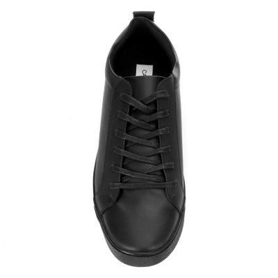 Ténis preto com atacadores sobre fundo branco