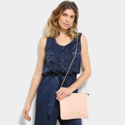 Mala pequena rosa claro com alça corrente dourada e mulher com macacão azul escuro