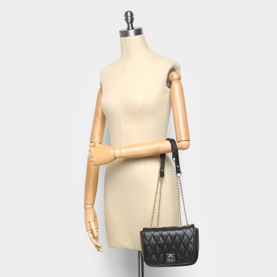 Mala preta matelassé com corrente dourada e fecho dourado no braço de manequim