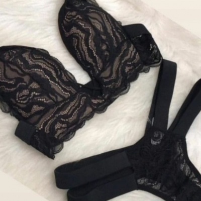 Conjunto de lingerie preta em renda sobre fundo branco felpudo