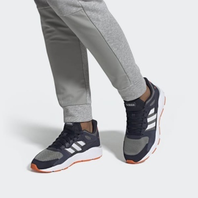 Ténis desportivos Adidas cinzentos com sola branca e laranja, usados com calças cinzentas