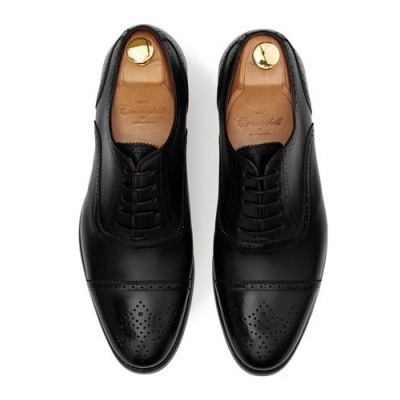 Sapatos masculinos pretos de couro com perfurações decorativas e atacadores.