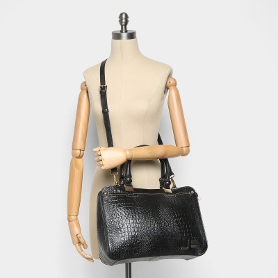 Mala de mão preta com padrão imitação pele de crocodilo em manequim