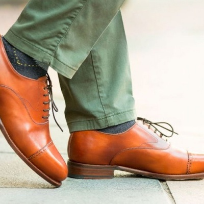 Sapatos de couro castanho com atacadores pretos em chão de pedras claras