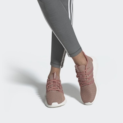 Ténis rosa com atacadores e etiqueta adidas, usados com leggings cinzentas, fundo branco