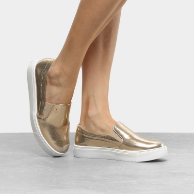 Ténis slip-on dourados metálicos com sola branca em pé