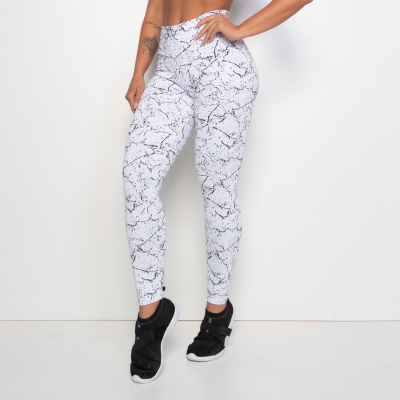 Leggings brancas com padrão preto de rachaduras em fundo branco, pernas visíveis até os pés com tênis pretos.