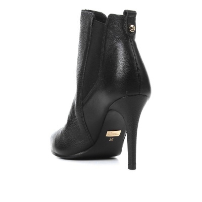 Botim feminino de salto alto preto em pele com salto fino e etiqueta dourada