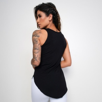 Mulher de costas vestindo top preto sem mangas e leggings brancas em fundo branco