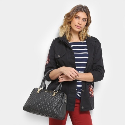 Mulher a segurar sacola preta acolchoada com alças e casaco bordado preto