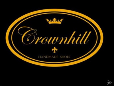 Logótipo Crownhill com coroa e texto Handmade Shoes em oval preto com borda alaranjada