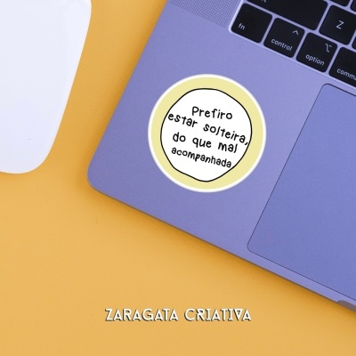 Computador portátil cinza com autocolante e rato branco sobre fundo amarelo