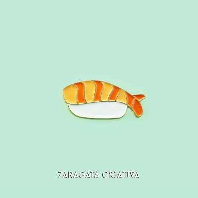 Pin em forma de sushi de salmão sobre fundo verde claro com texto ZARAGATA CRIATIVA