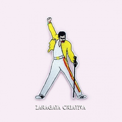Emblema bordado com figura humana de roupa branca e casaco amarelo, texto ZARAGATA CRIATIVA