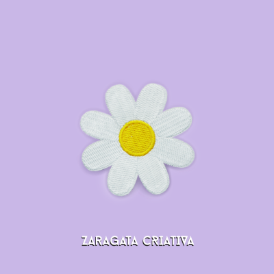 Patch bordado flor branca com centro amarelo no fundo lilás e texto ZARAGATA CRIATIVA