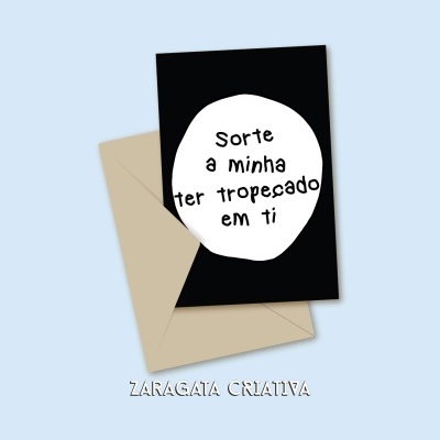 Cartão preto com mensagem em círculo branco e envelope castanho claro num fundo azul claro