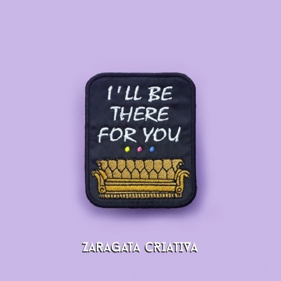 Emblema tecido preto com bordado texto e sofá amarelo sobre fundo lilás