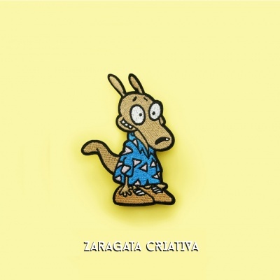 Pin em tecido de personagem animal animada com camisa azul sobre fundo amarelo