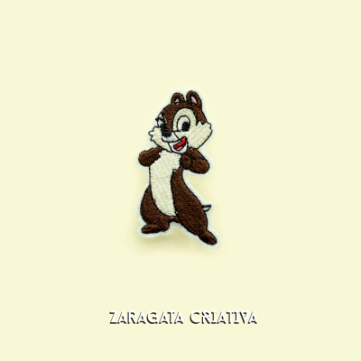 Bordado de esquilo sorridente com texto ZARAGATA CRIATIVA no fundo amarelo claro