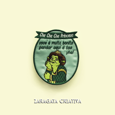Emblema bordado Che Che Che Princesa com texto em português e personagem, sobre fundo creme.