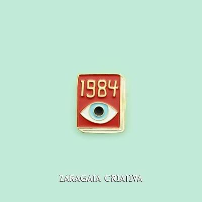 Pin metálico com design de livro '1984' e olho sobre fundo verde