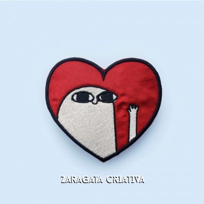 Emblema bordado de coração vermelho com figura branca e óculos pretos em fundo azul claro