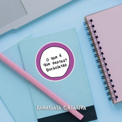 Cadernos pequenos azuis com escrita e lápis rosa ao lado de caderno espiral rosa