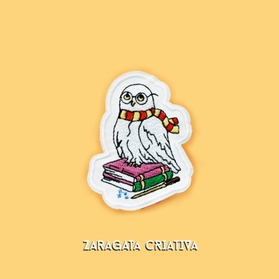 Patch bordado de coruja com lenço e livros em fundo amarelo