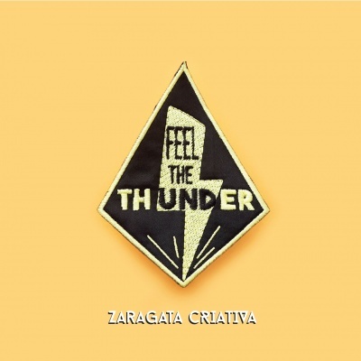 Emblema bordado preto e amarelo com raio e texto 'FEEL THE THUNDER'