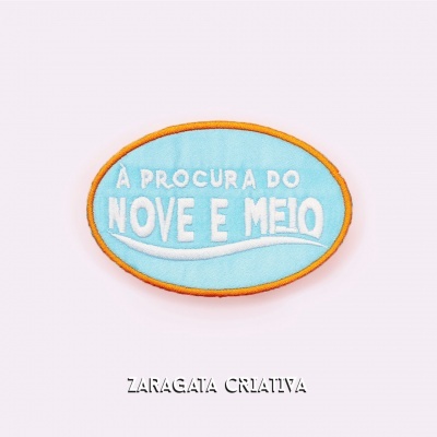 Emblema oval azul claro com texto branco e borda laranja