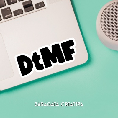 Portátil prateado com autocolante DtMF e coluna cinza em superfície verde água