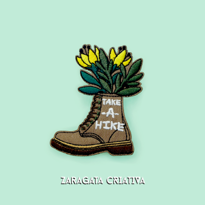 Patch bordado de bota castanha com flores amarelas e texto TAKE A HIKE