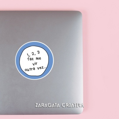 Computador portátil cinzento com autocolante azul e branco e lápis sobre fundo rosa