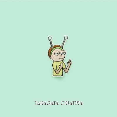 Bordado de personagem animado com antenas e expressão desdenhosa sobre fundo verde claro