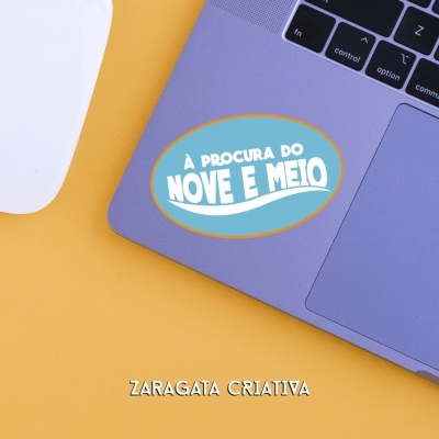 Computador portátil com autocolante azul e rato branco numa superfície amarela