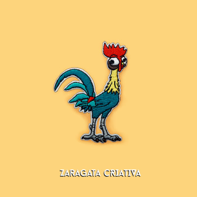 Aplicação bordada de galo colorido sobre fundo amarelo com texto ZARAGATA CRIATIVA