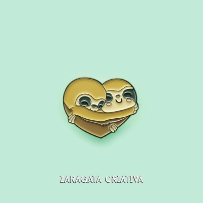 Pin metálico de dois preguiças a formar um coração com o texto ZARAGATA CRIATIVA