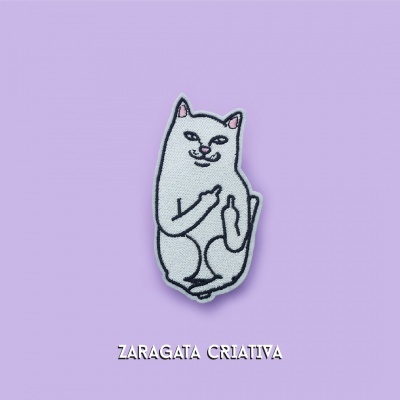 Distintivo bordado de gato branco a mostrar os dedos do meio, sobre fundo lilás com texto Zaragata Criativa
