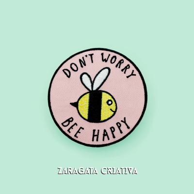 Emblema bordado redondo com abelha e texto motivacional em fundo rosa