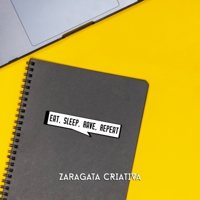 Caderno cinzento com etiqueta branca e texto em inglês ao lado de portátil prateado sobre fundo amarelo.