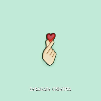 Pin de mão com coração vermelho em fundo verde claro e texto ZARAGATA CRIATIVA.