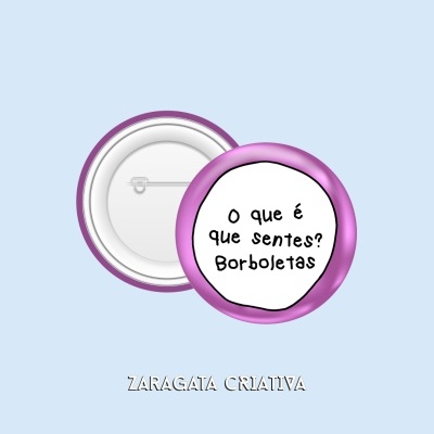 Dois bottons redondos em metal branco com bordinha roxa, texto em português 'O que é que sentes? Borboletas' visível no da frente.