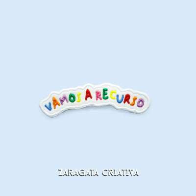 Aplicação em tecido com letras coloridas VAMOS A RECURSO sobre fundo azul claro