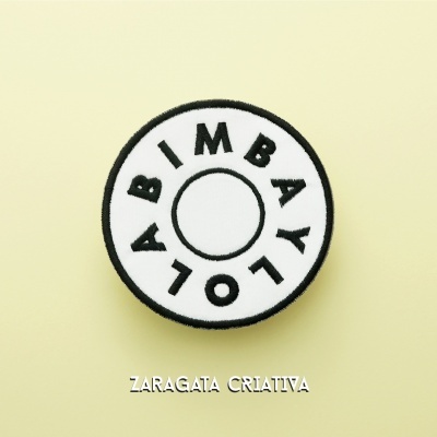 Patch bordado circular com letras pretas em fundo branco e borda preta